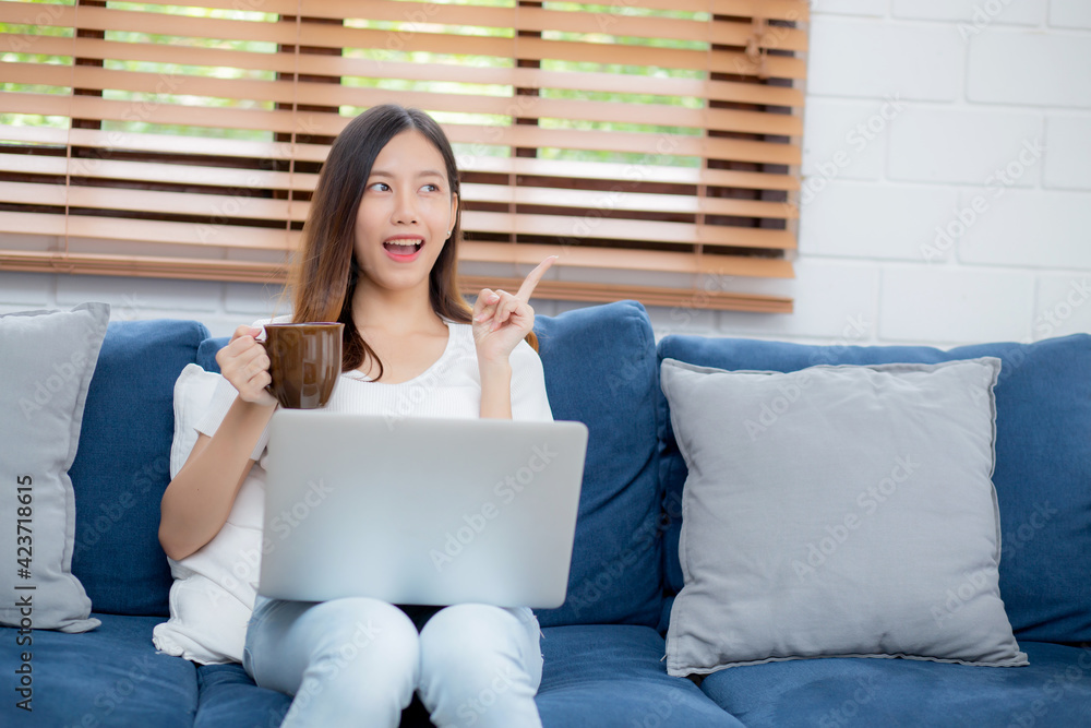 Young asian business woman smile and work from home with laptop computer online on sofa in living room, freelance girl using notebook and drink coffee on couch, new normal, lifestyle concept. Young asian business woman smile and work from home with laptop computer online on sofa in living room, freelance girl using notebook and drink coffee on couch, new normal, lifestyle concept.