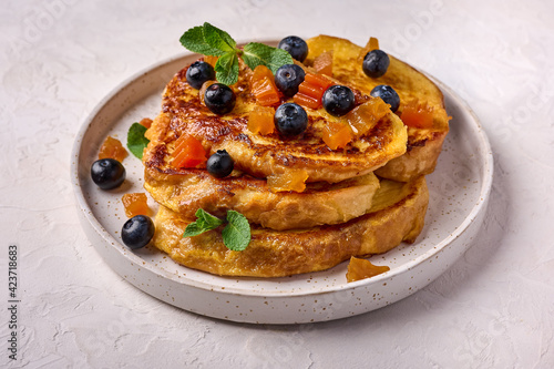 Homemade traditional Spanish torrijas or French toast with melon candied fruit and blueberries. Popular dessert for Christmas, Easter or Pascua. Close up