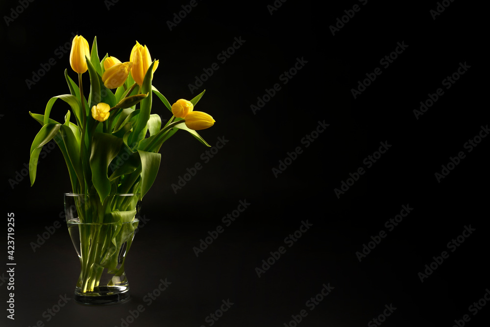Yellow tulips on a black background, top view, spring bouquet in a vase Yellow tulips on a black background, top view, spring bouquet in a vase