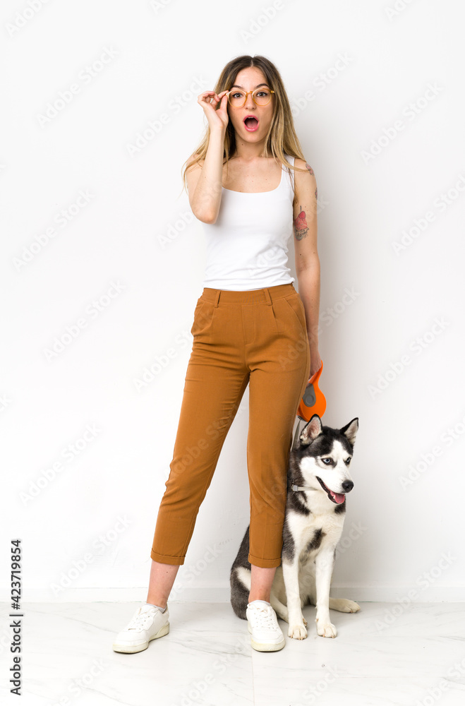 A full length young pretty woman with her dog with glasses and surprised