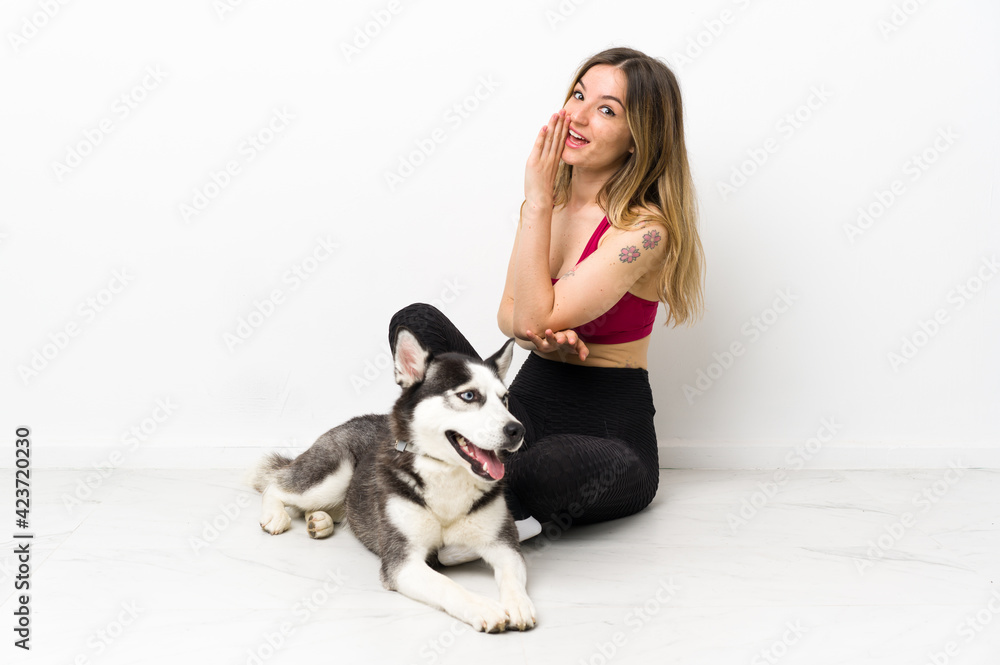 Young sport girl with her dog sitting on the floor whispering something Young sport girl with her dog sitting on the floor whispering something
