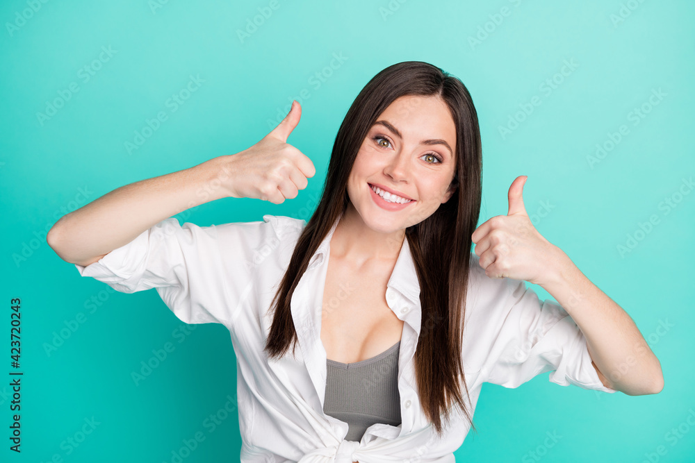 Photo of attractive cheerful happy young woman make thumbs up smile choose isolated on teal color background Photo of attractive cheerful happy young woman make thumbs up smile choose isolated on teal color background