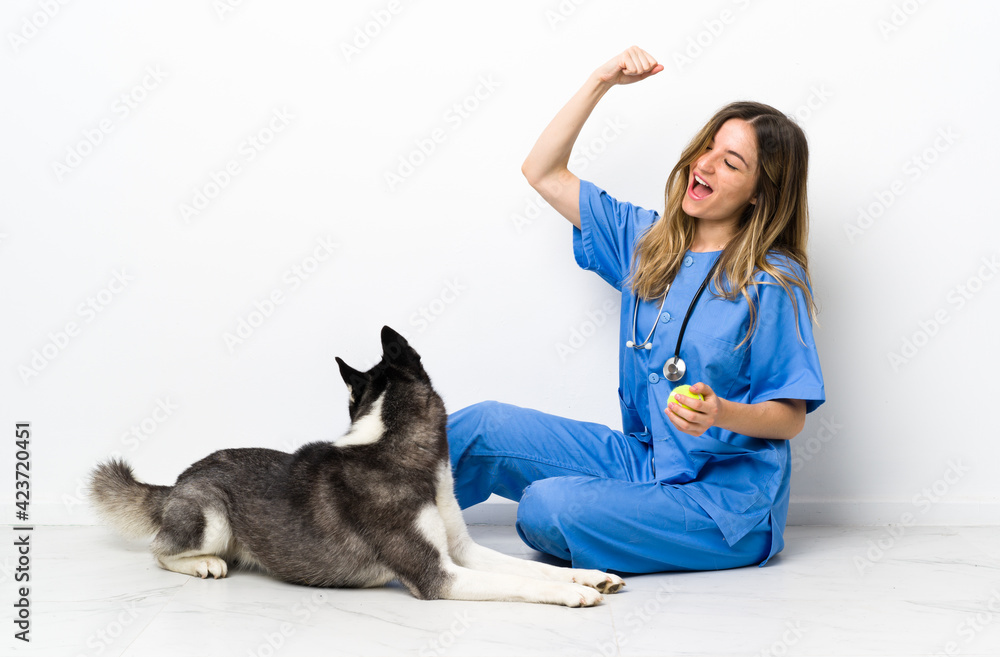 Veterinary doctor with Siberian Husky dog sitting on the floor celebrating a victory Veterinary doctor with Siberian Husky dog sitting on the floor celebrating a victory