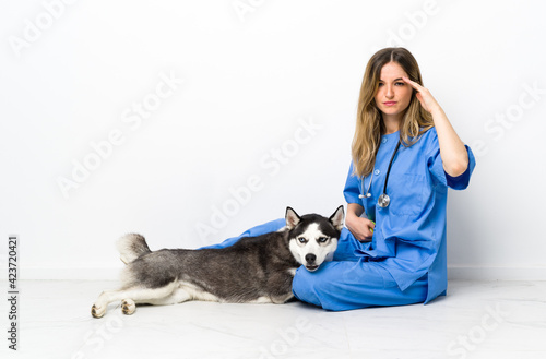 Veterinary doctor with Siberian Husky dog sitting on the floor unhappy and frustrated with something. Negative facial expression