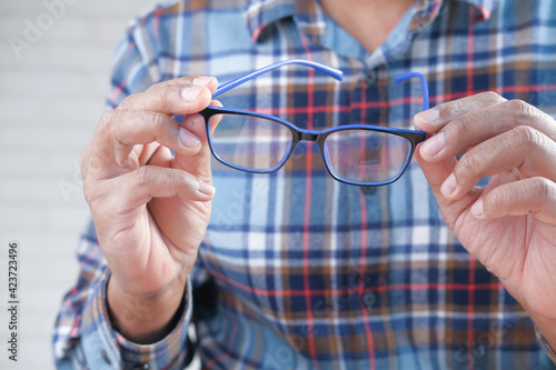 Close up of man hand holding eyeglass in dark.