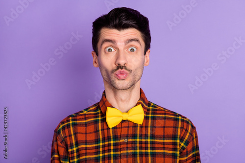 Photo of funny attractive young guy wear plaid shirt sending kiss isolated violet color background
