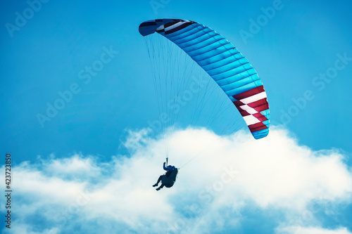 Paraglider flying over the mountains. Active people enjoying in extreme and adrenalin sports.