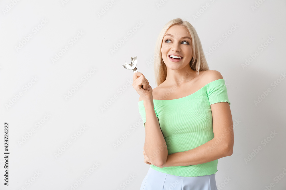 Young woman with dental tool for making mold of teeth on light background Young woman with dental tool for making mold of teeth on light background