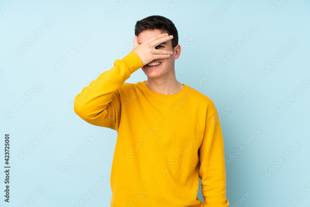 Teenager caucasian handsome man isolated on purple background covering eyes by hands and smiling Teenager caucasian handsome man isolated on purple background covering eyes by hands and smiling