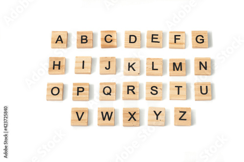 Top view of english alphabet made of square wooden tiles with the English alphabet scattered on a white background with space for text. The concept of thinking development, grammar.