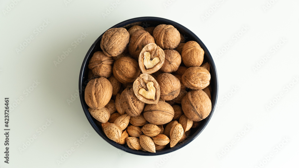 almonds and walnuts in a plate on a white background almonds and walnuts in a plate on a white background