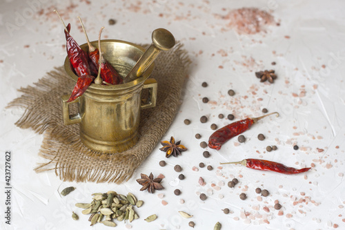 Copper mortar with chilly pepper and spices on a white table