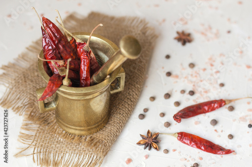 Copper mortar with chilly pepper and spices on a white table