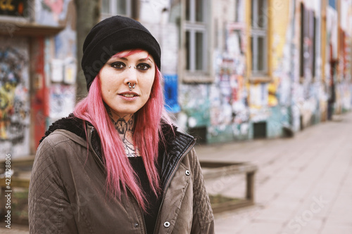 pierced and inked young woman in front of run-down graffiti covered houses photo
