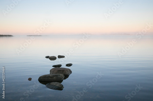 Принти на полотні Beautiful sea bay scenery with the row of stones on the calm sunrise colored wat