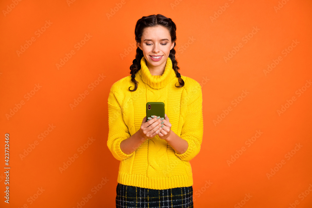 Photo of brown hair optimistic girl hold telephone wear yellow sweater isolated on orange color background Photo of brown hair optimistic girl hold telephone wear yellow sweater isolated on orange color background