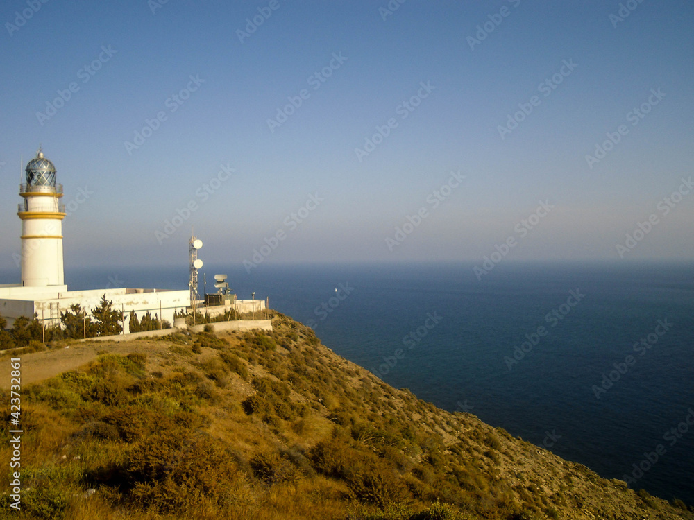 white lighthouse on top of a hill with ocean view