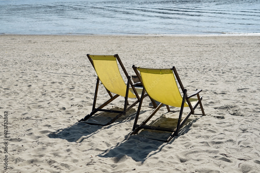 Two  yellow beach chairs  on the sand  by the river