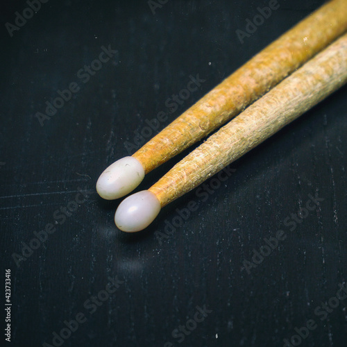 Used wooden drumsticks with white tips on dark background