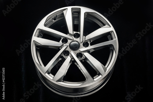 new shiny alloy wheel on black background, front view