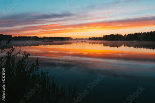 Colorful sunset over the Lielais Ansis lake in Latvia. Sunset reflections in the water over the wakeboard park