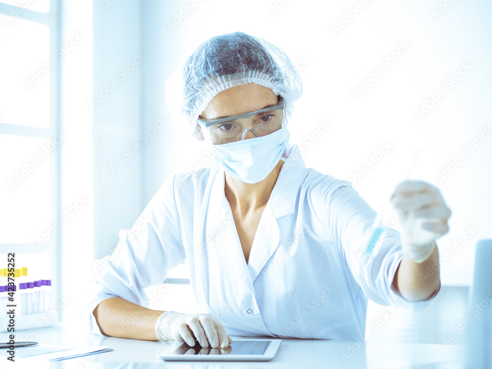 Professional female scientist in protective eyeglasses researching tube with reagents in laboratory. Concepts of medicine and research Professional female scientist in protective eyeglasses researching tube with reagents in laboratory. Concepts of medicine and research