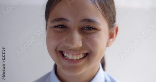 Slow motion close-up scene of a cute young teenage girl student is smiling happily.