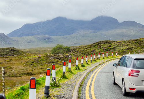 Car driving on the left hand side of the road in rural area of Scotland, UK, Europe. Left-hand traffic concept.