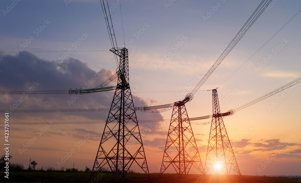 power line pylons during sunset with beautiful saturated sky. distribution transmission and consumption of electricity