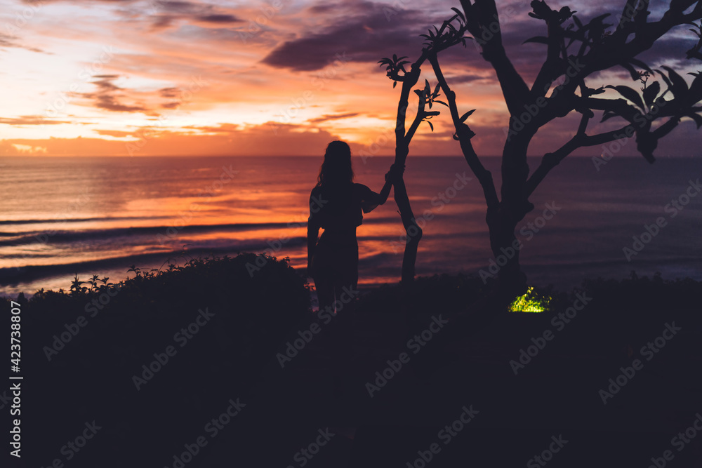 Fototapeta premium Anonymous woman standing on coast and looking at ocean