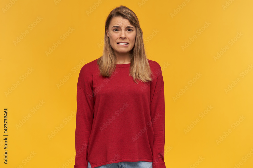 Girl looks looks with disgust, frowns, mouth opened, keeps mobile phone in her hand, black screen turned to the camera, points on it with index finger, isolated on a yellow studio background Girl looks looks with disgust, frowns, mouth opened, keeps mobile phone in her hand, black screen turned to the camera, points on it with index finger, isolated on a yellow studio background