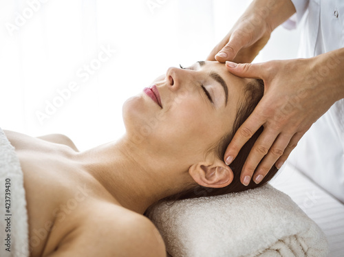 Beautiful brunette woman enjoying facial massage comfortable and bissfulle. Relaxing treatment in medicine and spa center concepts