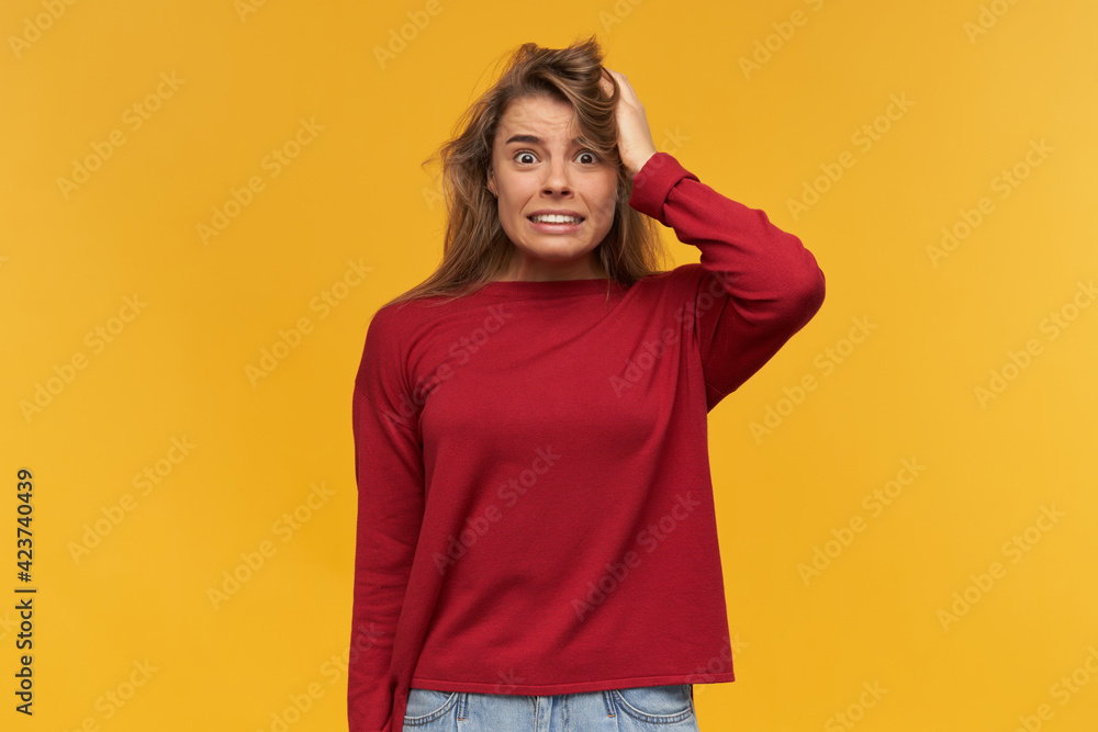 Shocked unsatisfied blonde girl looks indignantly, mouth opened wide, froze with indignation, wearing casual red sweater, standing isolated over yellow background Shocked unsatisfied blonde girl looks indignantly, mouth opened wide, froze with indignation, wearing casual red sweater, standing isolated over yellow background