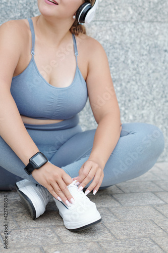Cropped image of plus size fit young woman resting on ground aftrer working out outdoors