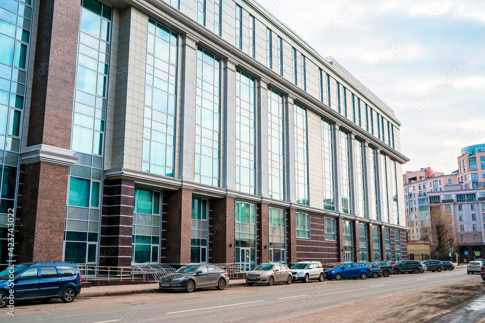 Glass business building and parked cars. St Petersburg, Russia - 28 Mar 2021