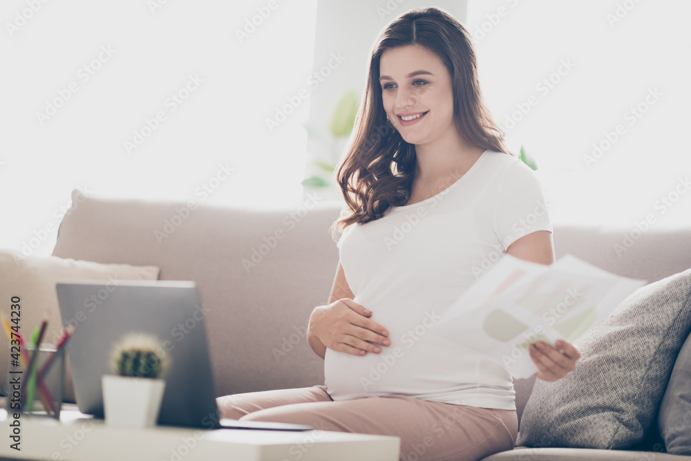 Photo of young attractive beautiful happy positive smiling pregnant woman hold documents working at home house Photo of young attractive beautiful happy positive smiling pregnant woman hold documents working at home house