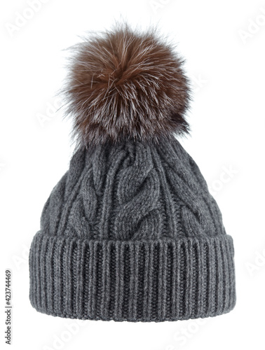 Beautiful knitted dark gray winter hat made of wool yarn with a fluffy fur pompom made of black-brown Fox, isolated on a white background.