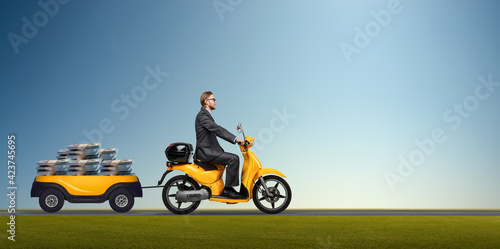 businessman goes on yellow scooter with trailer carted money of dollars