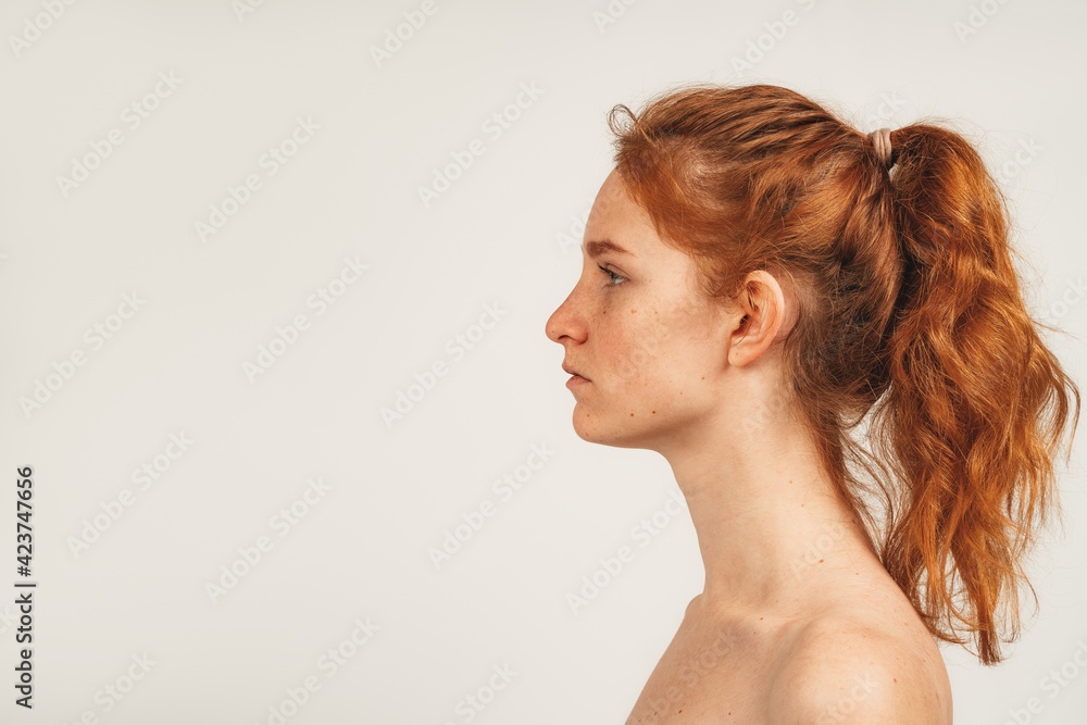 Close up face in profile natural redhead cute woman with freckles. Isolated over white background. Natural beauty and health Close up face in profile natural redhead cute woman with freckles. Isolated over white background. Natural beauty and health