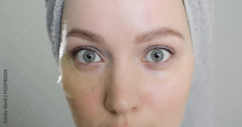 Side view of beautiful caucasian woman using eye patches after spa before going out on gray background. Concept of self-care and anti-aging treatments Side view of beautiful caucasian woman using eye patches after spa before going out on gray background. Concept of self-care and anti-aging treatments