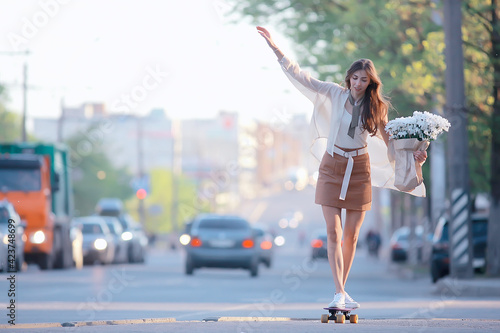 girl riding a skate in the city / model young adult girl on the street in full growth, board on wheels