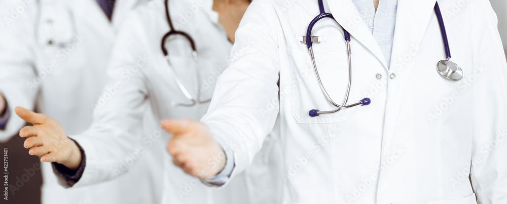 Group of doctors are standing as a team while offering their helping hands for shaking hand or saving people's life. Medicine concept during Coronavirus pandemic. Covid-2019 Group of doctors are standing as a team while offering their helping hands for shaking hand or saving people's life. Medicine concept during Coronavirus pandemic. Covid-2019