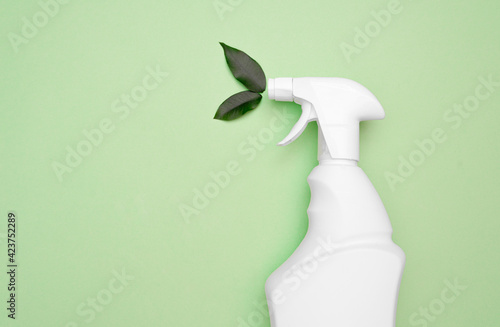Safe general cleaning, environmentally friendly detergent. Eco bottle white spray for safe and natural cleaning at home and office, green leaves on a green background. top view, Flat lay, copy space 