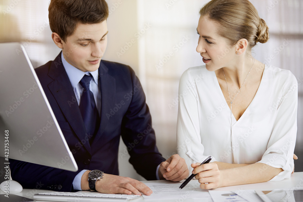 Business people discussing something while sitting in sunny office. Focus at businesswoman while talking to her male colleague Business people discussing something while sitting in sunny office. Focus at businesswoman while talking to her male colleague