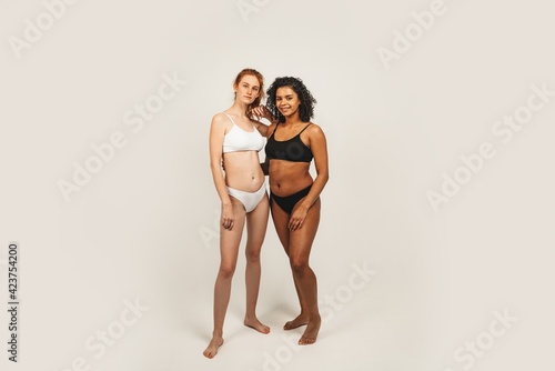 Photo of natural multiracial women, body positive. Feminist females in underwear stand, isolated on white background. Concept natural beauty and girl power