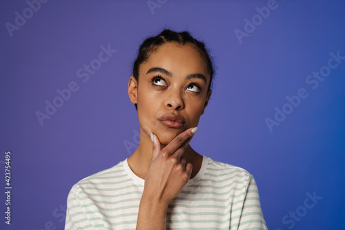 Young black woman in t-shirt thinking and looking upward