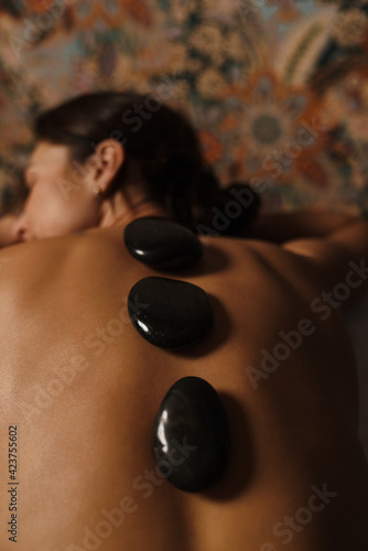 White relaxed shirtless woman lying during spa treatment with stones