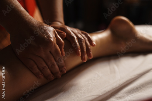 Professional masseuse doing foot massage with oil in spa