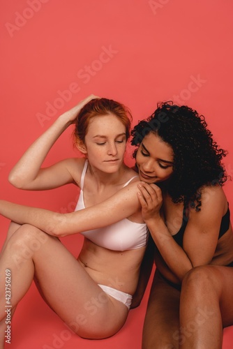 Photo of natural multiracial women, body positive. Feminist females sit isolated on pink background. Concept natural beauty and girl power © Ivan