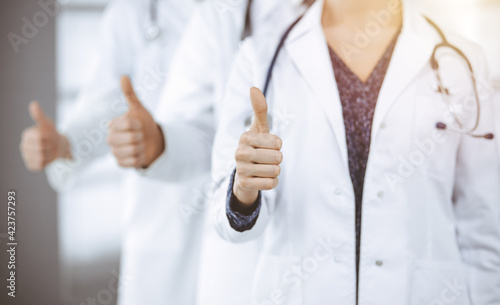 Doctors standing as a team with thumbs up in sunny clinic and ready to help patients. Medical help, insurance and medicine concept